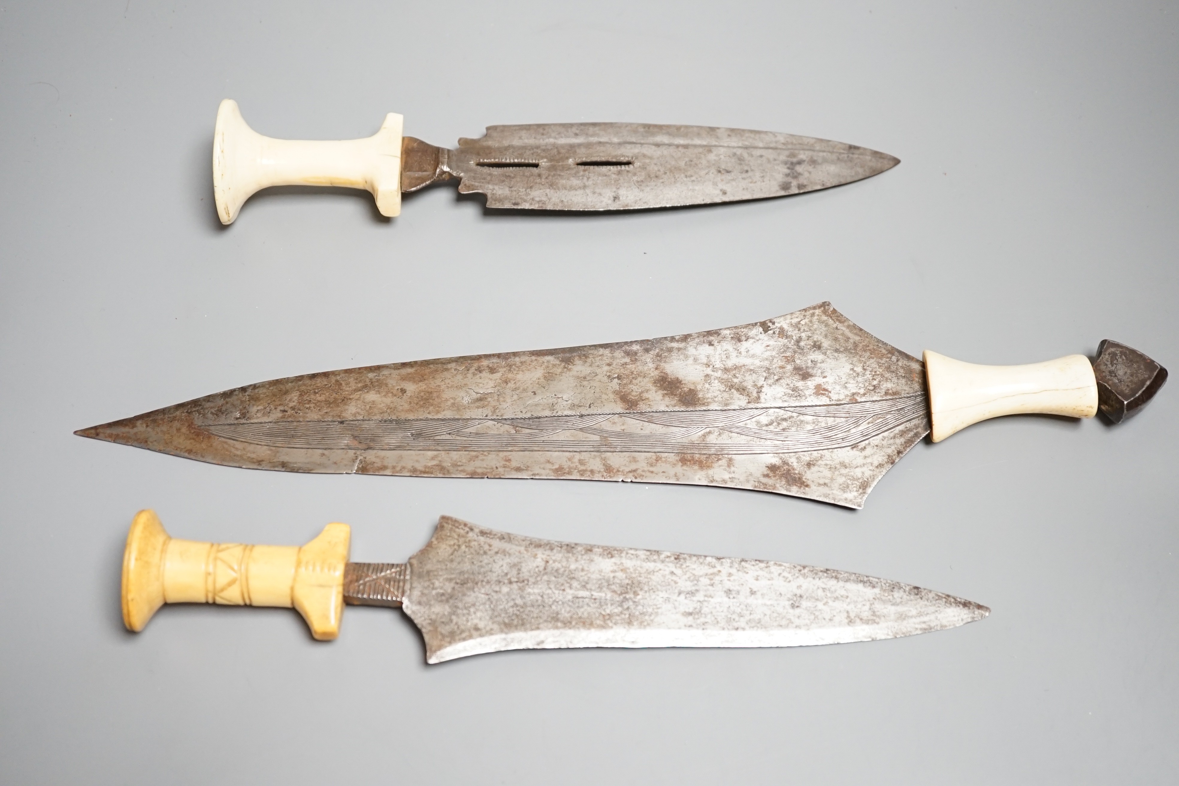 Three assorted African tribal daggers c.1900, each with ivory handle including two with decorated blades and one with iron pommel, maximum 40cms